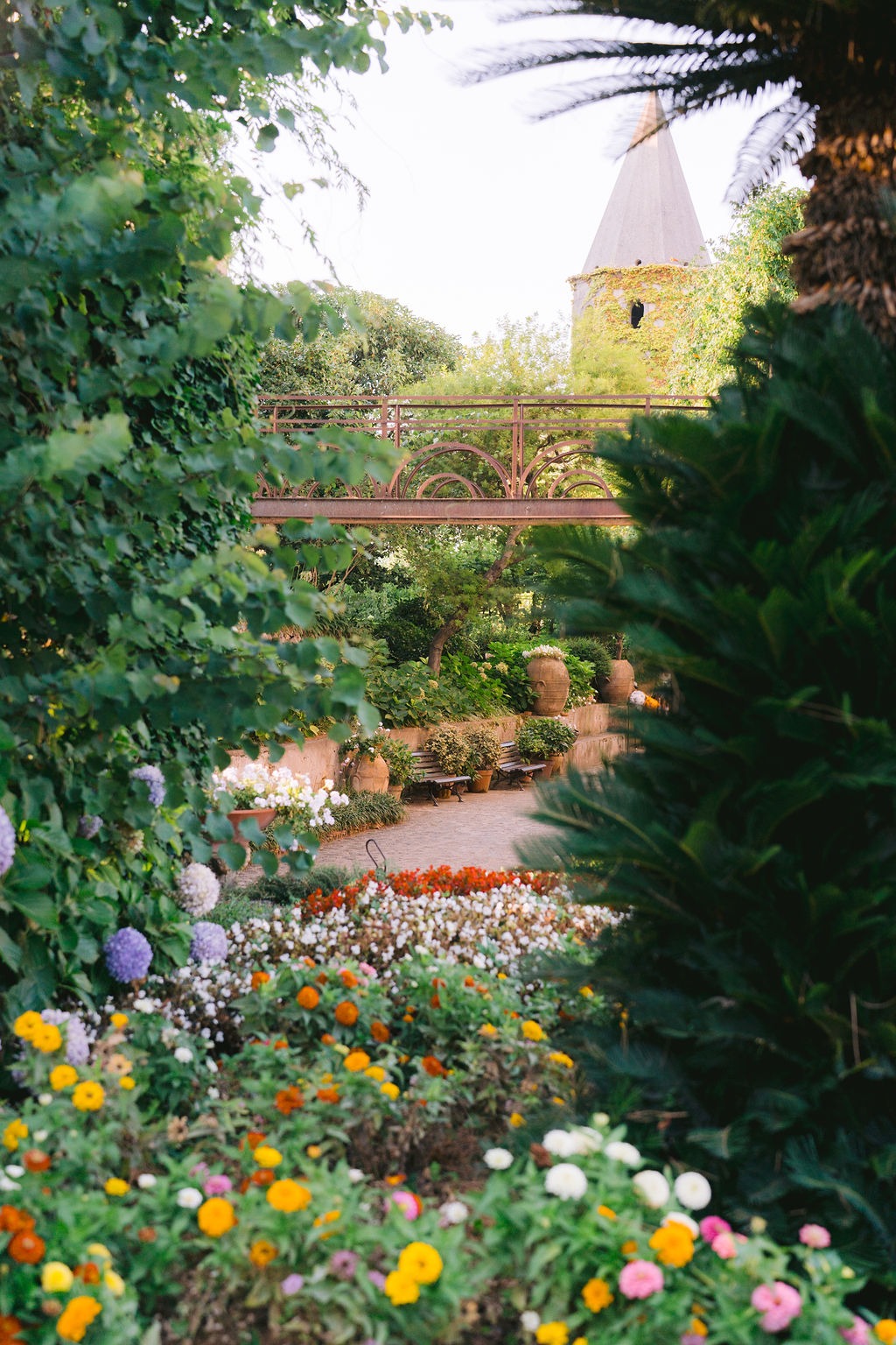 A vibrant garden with colorful flowers and lush greenery at Villa Cimbrone, with a tower visible in the background.