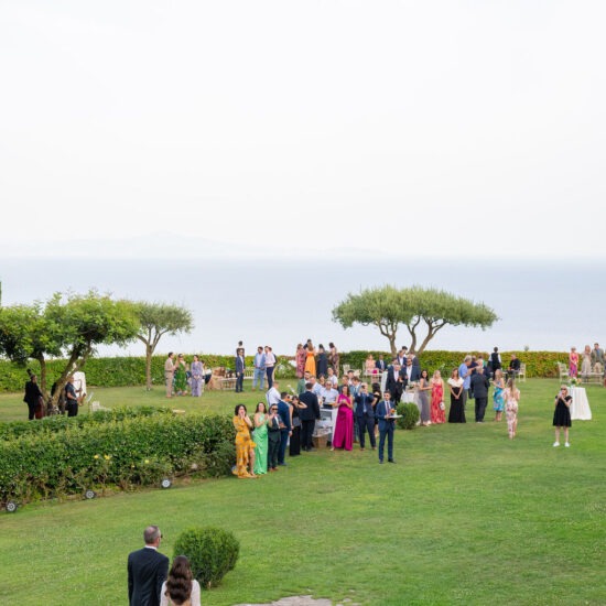 Guests gathered in the expansive gardens of Villa Cimbrone, with a view of the sea in the background.