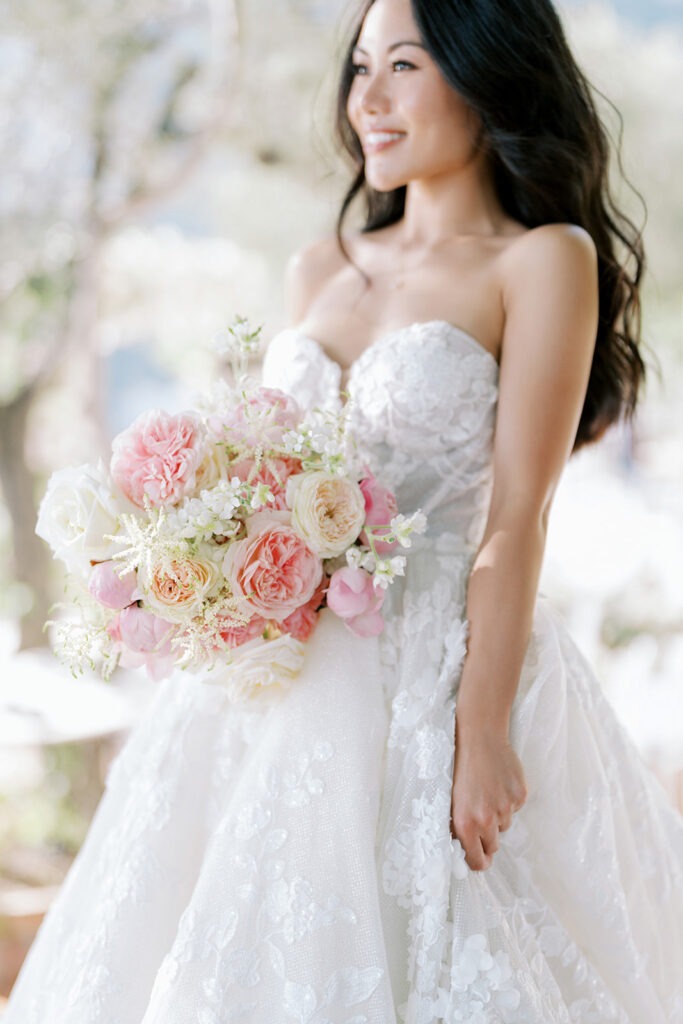 Close-up of the bride holding a pastel bouquet, smiling softly in natural light.