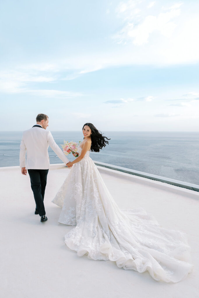 Bride and groom looking deeply into each other’s eyes with a dramatic coastline in the background.